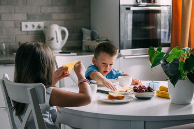 Sister and brother with food on table at home