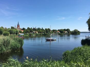 Sailboats in river by temple against sky