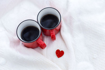 Romantic still life, two red cups of coffee on a white plaid. valentine's day concept.