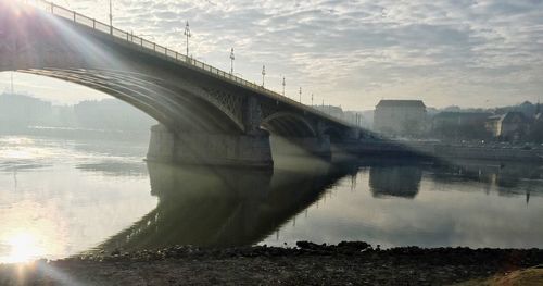 Arch bridge over river against sky during sunny day