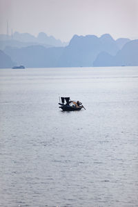 Boat sailing on sea against mountains