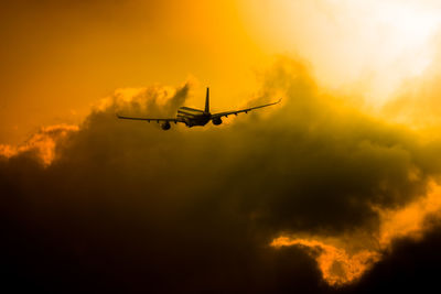 Low angle view of silhouette airplane against sky during sunset