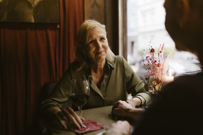 Smiling romantic woman looking at man during date at bar