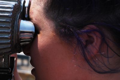 Close-up of woman looking through coin-operated binoculars