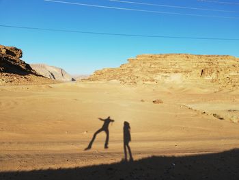 People on arid landscape against sky