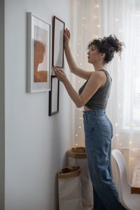 Side view of woman standing against wall at home