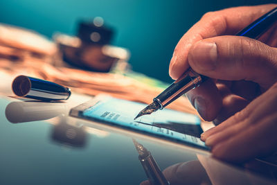 Close-up of hand writing on paycheck