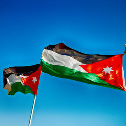 Low angle view of flag against clear blue sky