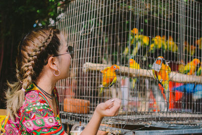 Woman looking at birds in cage