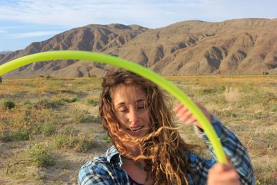 Woman holding plastic hoop against mountains and sky