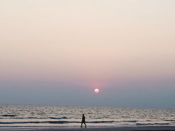 Silhouette person walking against sea during sunset