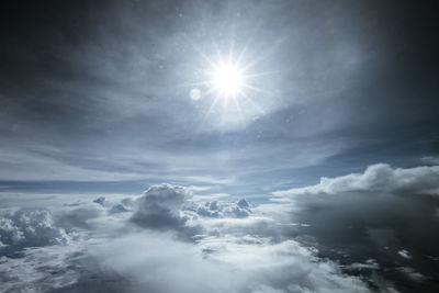 Low angle view of sunlight streaming through clouds