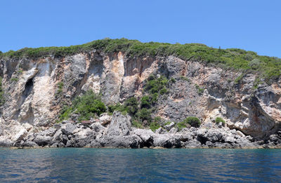 Rock formations by sea against clear sky