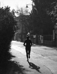 Rear view of man walking on footpath in city