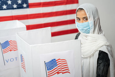 Portrait of woman wearing mask standing at voting booth