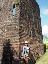 Full length of man standing against brick wall