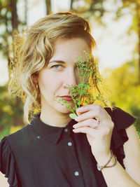 Portrait of young woman holding plant
