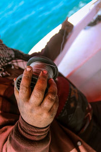 Midsection of man holding spool in boat on sea