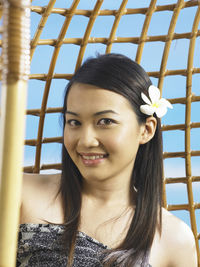 Close-up portrait of smiling young woman sitting on swing