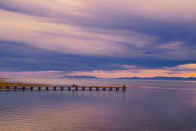 Pier over sea against sky during sunset