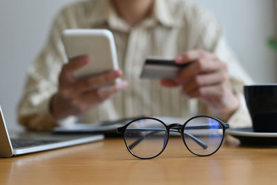 Midsection of man using mobile phone on table