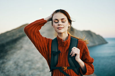 Young woman standing by sea against sky