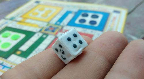 Hand holding dice, playing indoor game ludo board 