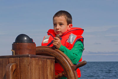 Side view of boy playing with toy against sea