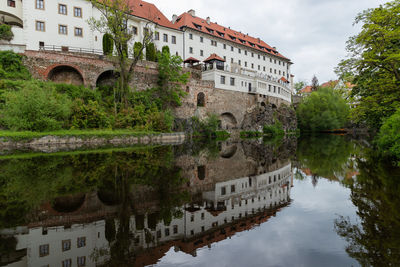 Arch bridge over river by buildings against sky