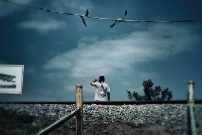 Low angle view of man photographing against sky