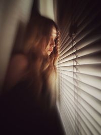 Woman looking through blinds