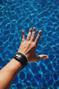 Cropped hand of man over swimming pool