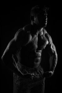 Midsection of shirtless man against black background