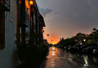 Street amidst buildings against sky during sunset