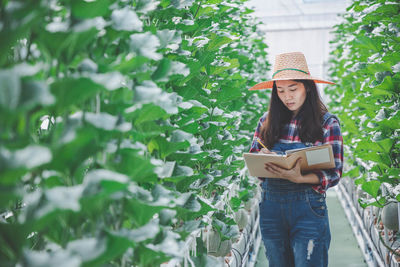 Woman wearing hat standing against plants