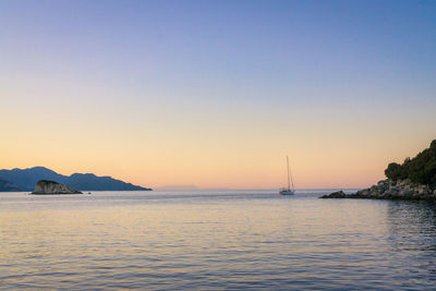 Sailboats sailing in sea against clear sky during sunset