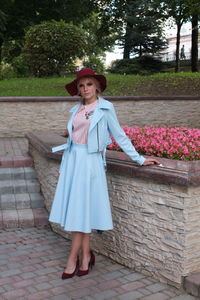 Portrait of woman standing by retaining wall