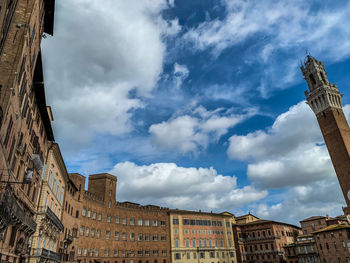 Low angle view of buildings in town against cloudy sky