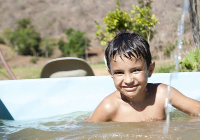 Portrait of shirtless boy swimming in pool against trees