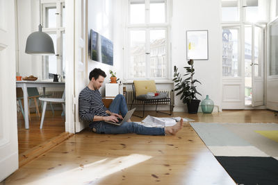 Man sitting in foor, using laptop, working from home