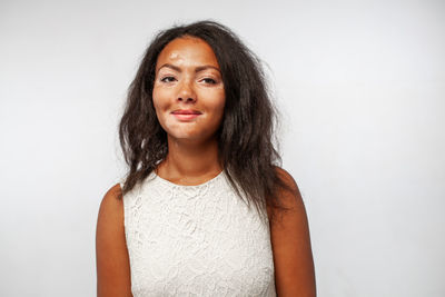 Portrait of young woman standing against white background