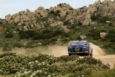 Cars on rock by road against sky