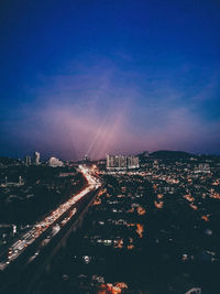 High angle view of illuminated buildings in city against blue sky