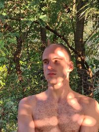 Portrait of shirtless young man against trees