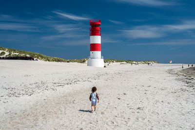 Lighthouse on beach against sky