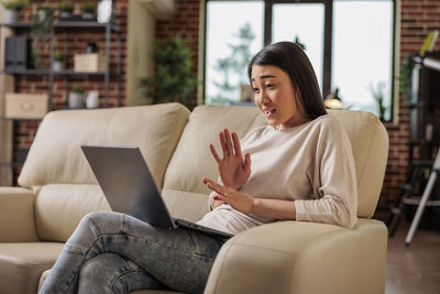 Young woman using laptop while sitting at home