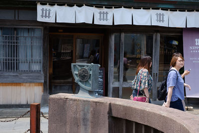 Women standing by window of building