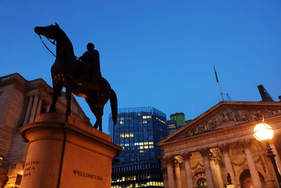 Low angle view of statue against illuminated city at night