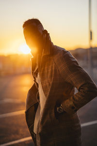 Young man standing against sky during sunset