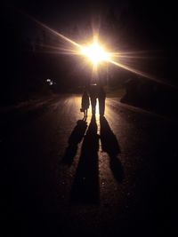 Silhouette people walking on road at sunset